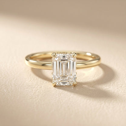 Emerald Cut Lab Grown Diamond Solitaire Engagement Ring in Yellow Gold on a light background