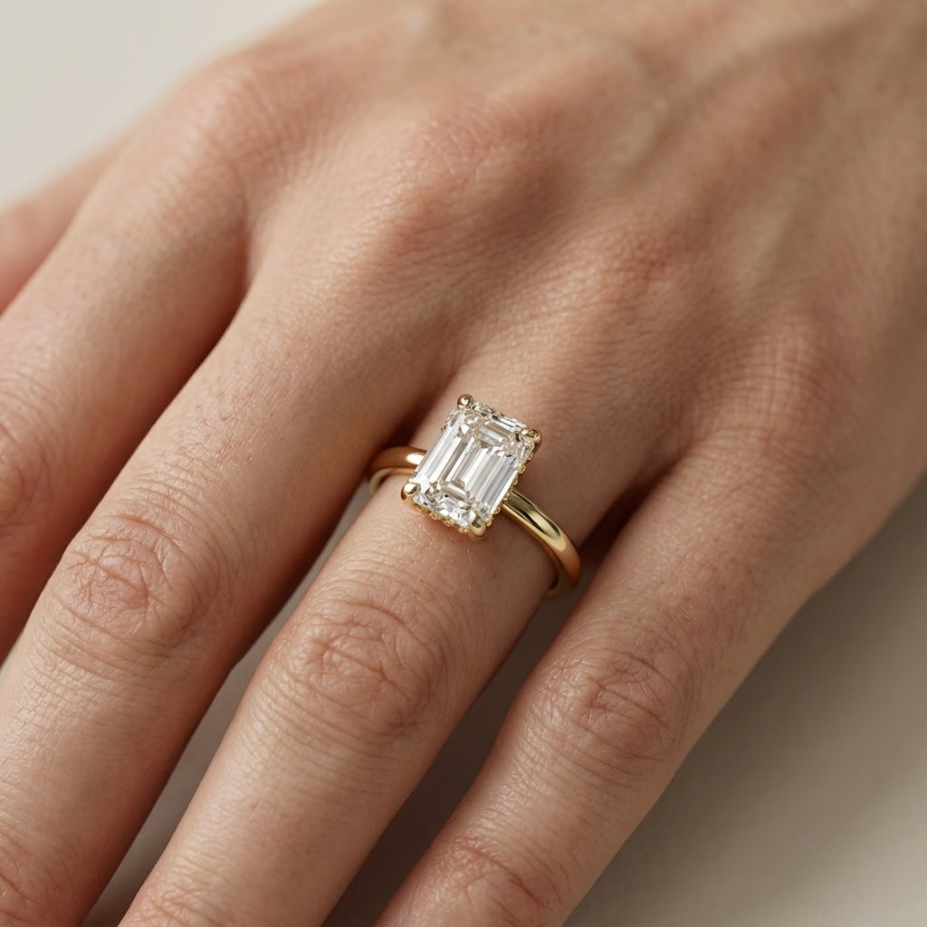 Emerald Cut Lab Grown Diamond Solitaire Engagement Ring in Yellow Gold on a light background