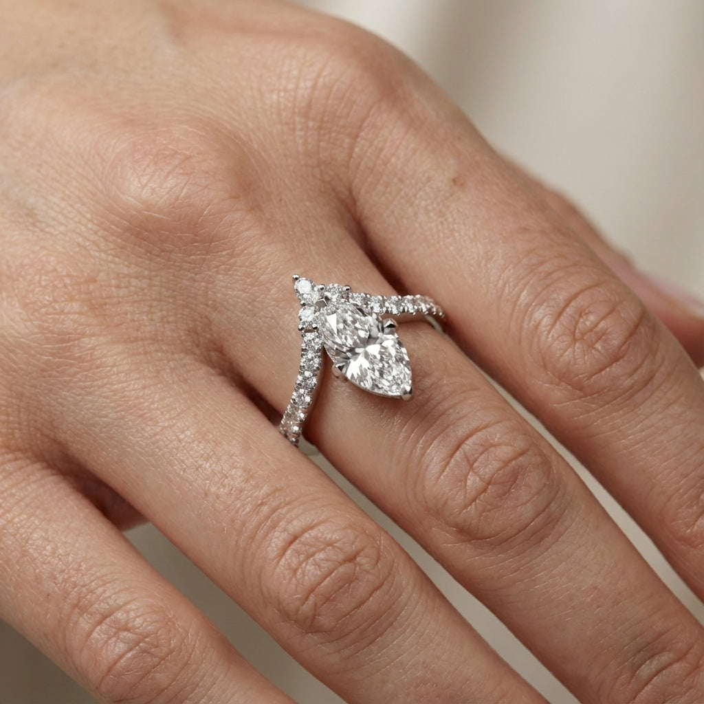 Marquise cut lab grown diamond engagement ring with side stones in a polished silver setting.