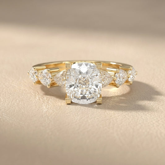 Cushion cut lab grown diamond engagement ring with marquise and pear side stones set in rich yellow gold.