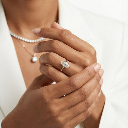 Yellow gold marquise cut lab grown diamond solitaire engagement ring with polished band and floral prongs.