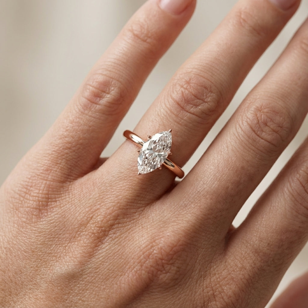 Yellow gold marquise cut lab grown diamond solitaire engagement ring with polished band and floral prongs.