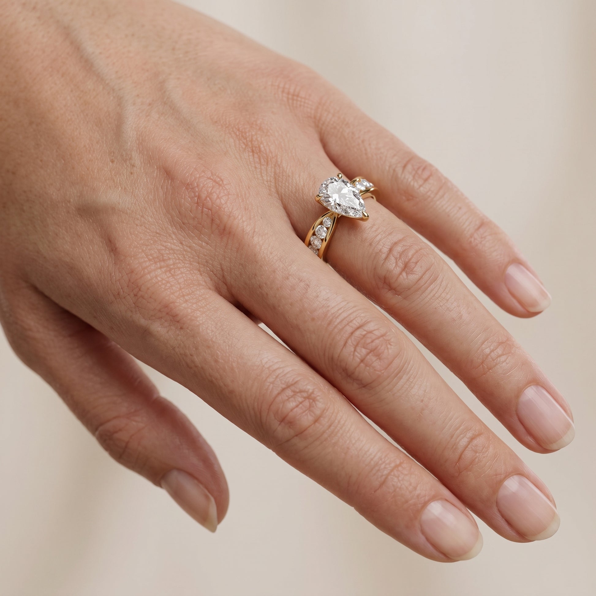 Noor Channel Set Sidestone Pear Diamond Engagement Ring in Yellow Gold - lifestyle.jpg